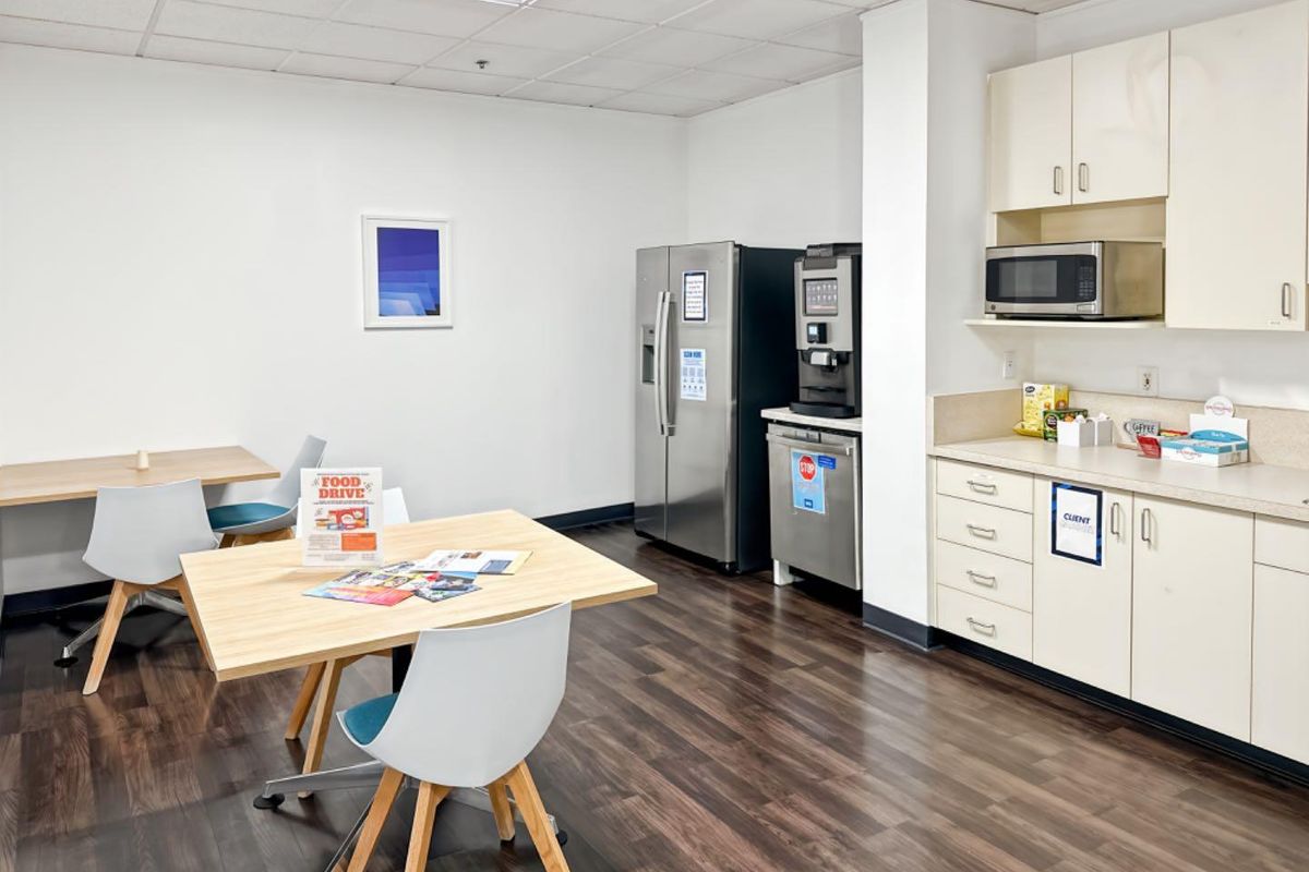 Office breakroom featuring laminate cabinetry, built-in microwave, vinyl plank flooring, and a drop ceiling, providing a functional space for staff.