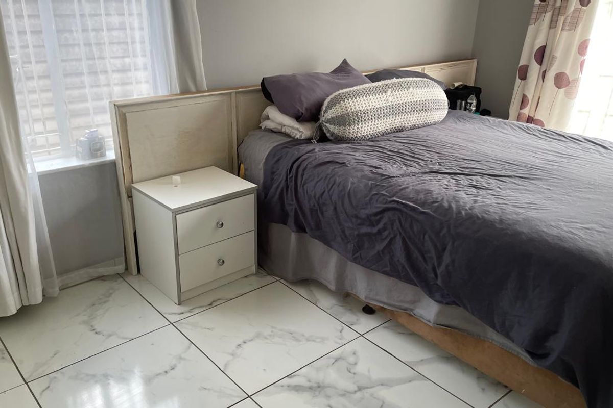 A well-maintained bedroom featuring modern marble-look floor tiles and a custom built-in headboard, offering a clean and neutral foundation for personal styling.