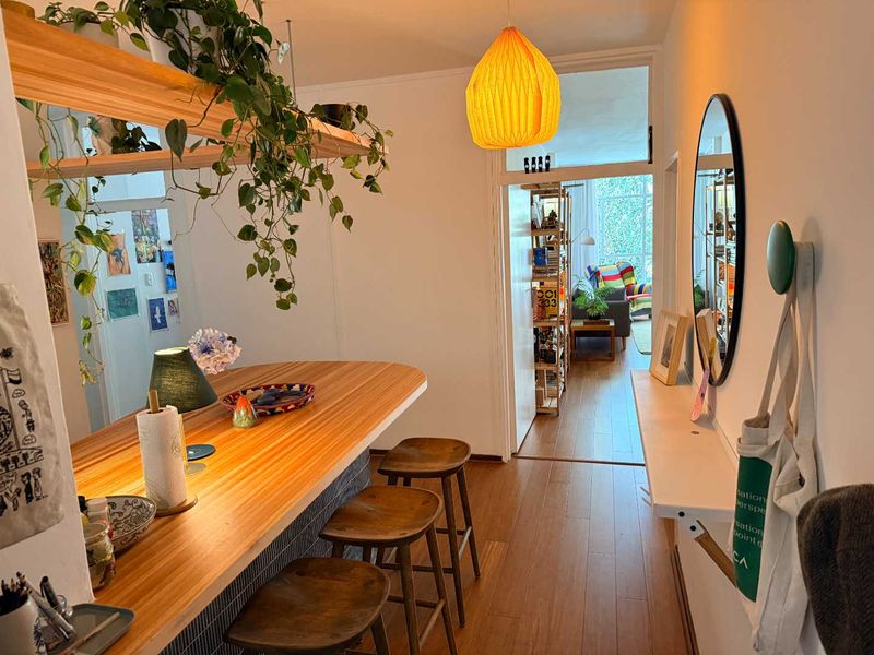 Open plan living area featuring a built-in breakfast bar with tiled base, wooden flooring, and a floating shelf, creating a functional and connected space.