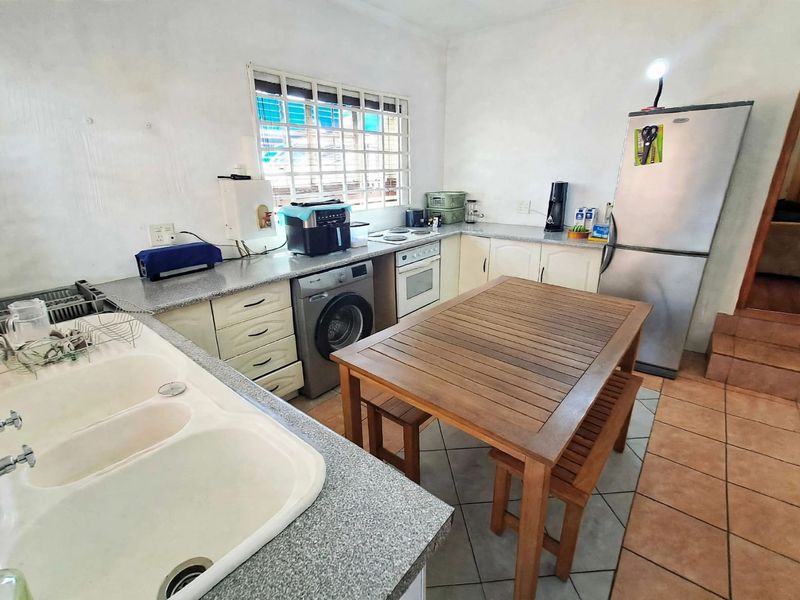 Functional kitchen featuring laminate countertops, double basin sink, built-in oven, hob, and tiled flooring with integrated laundry appliance space.