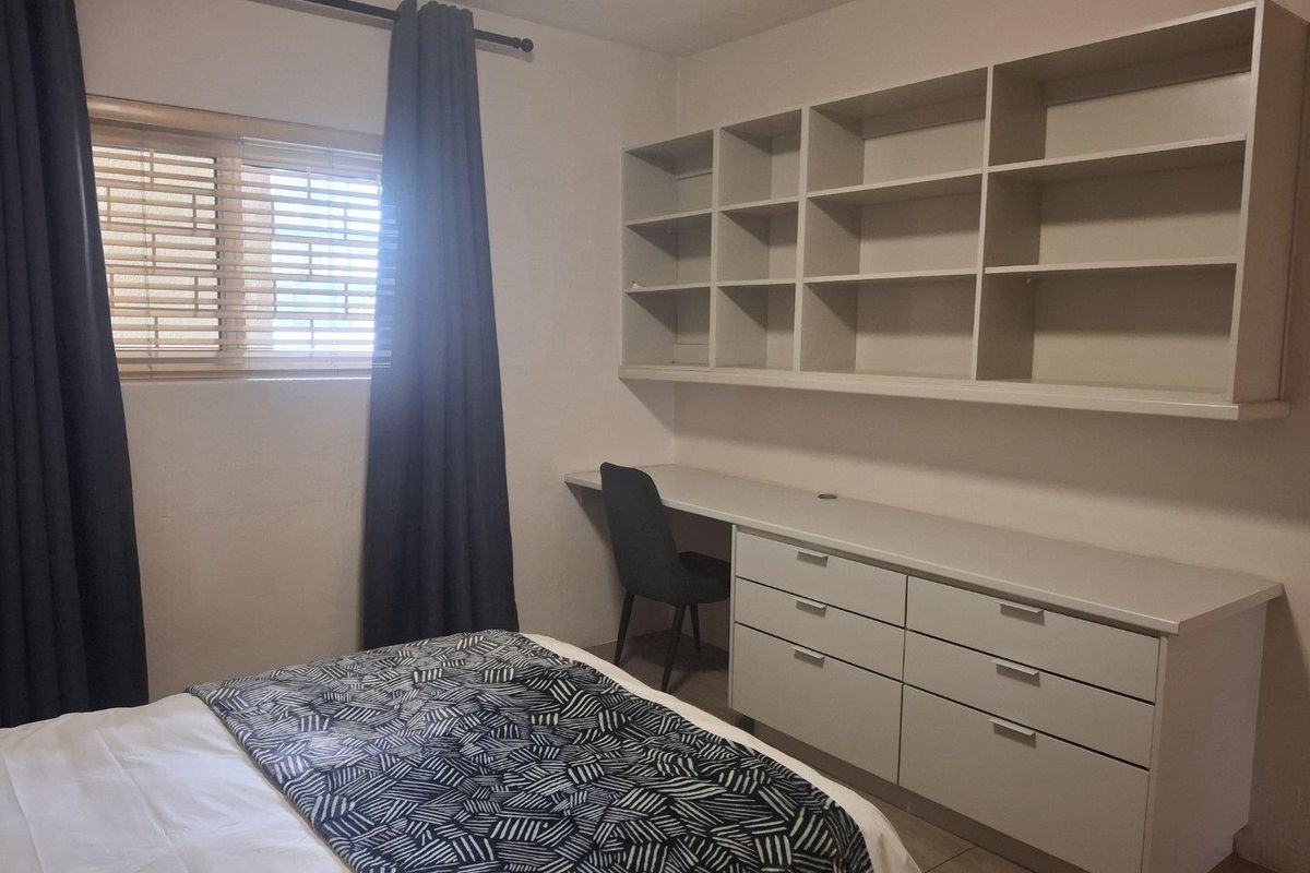 A bedroom featuring a functional built-in desk, integrated shelving, and drawer storage, providing efficient workspace and organization within the room.