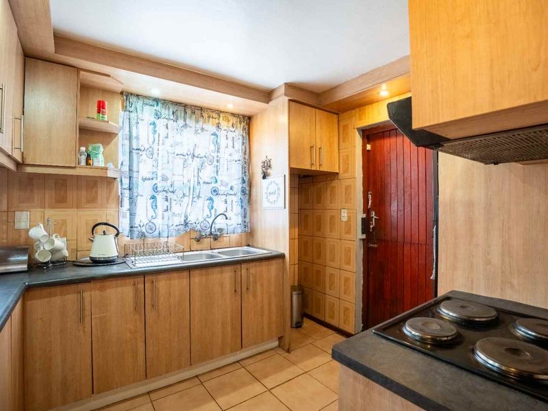 A functional kitchen featuring laminate cabinetry, a double sink, tiled backsplash, and a built-in electric hob with an extractor fan.