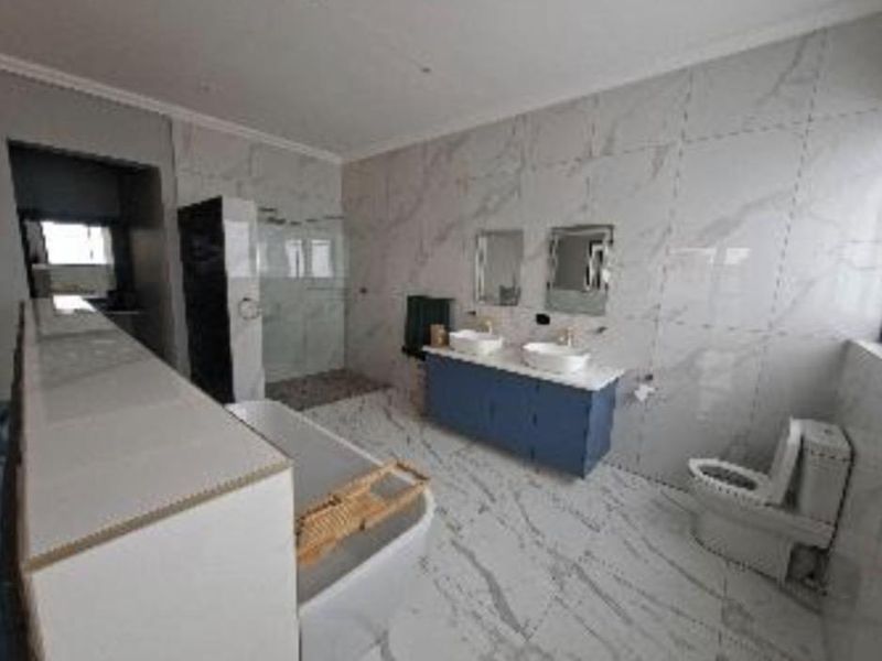 Modern bathroom featuring a double vanity, freestanding bathtub, walk-in shower, and floor-to-ceiling marble-style tiling.
