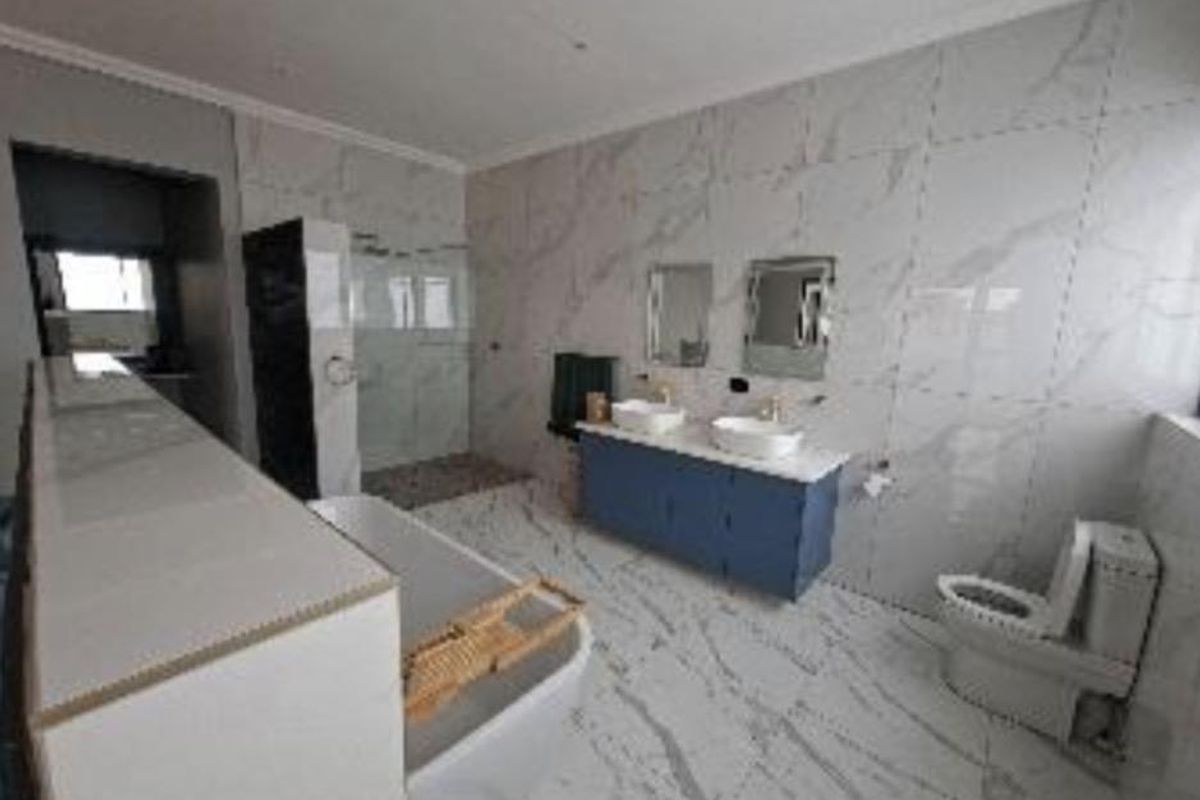 Modern bathroom featuring a double vanity, freestanding bathtub, walk-in shower, and floor-to-ceiling marble-style tiling.