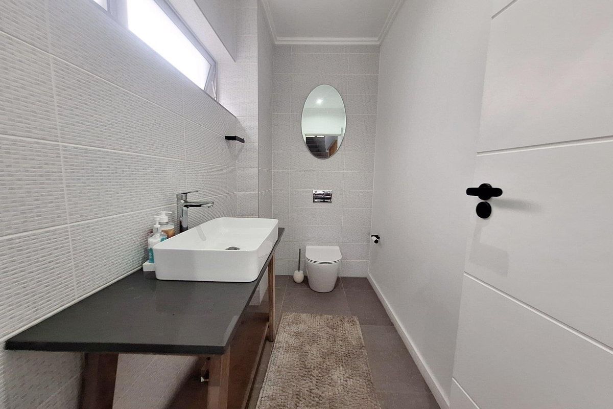 A modern, well-maintained bathroom featuring a vessel sink on a floating vanity, a back-to-wall toilet, and neutral tiled finishes.