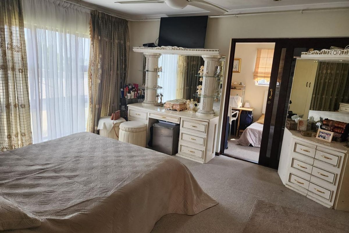 A spacious bedroom featuring neutral carpeting, a ceiling fan, and large sliding glass doors that provide ample natural light.