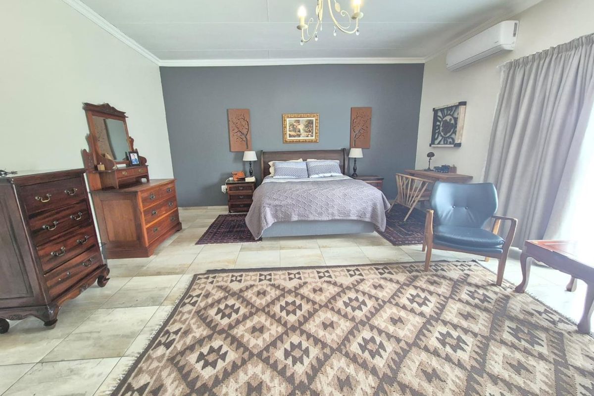 Spacious bedroom featuring tiled flooring, a feature accent wall, and a wall-mounted air conditioning unit.