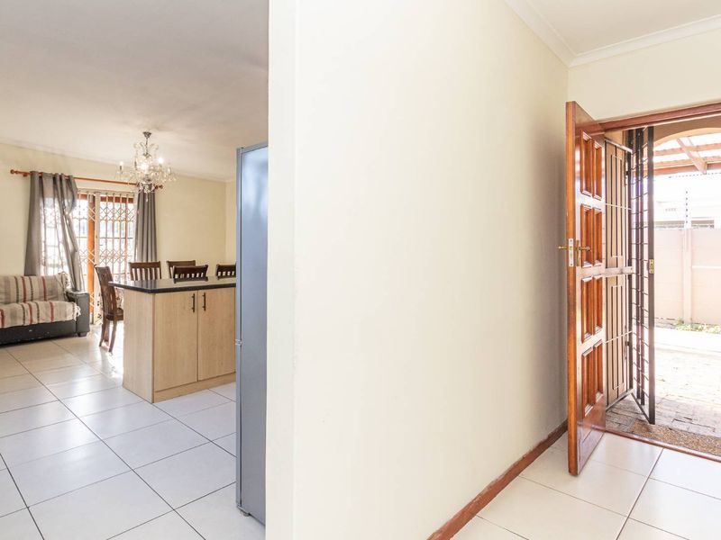Open plan living and dining area featuring tiled flooring, a central kitchen island, and direct access to the exterior through a security gate.