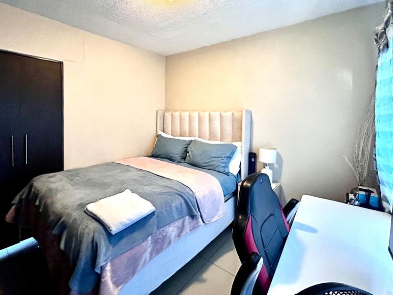 A functional bedroom featuring tiled flooring and a built-in wardrobe, providing essential storage and a neutral foundation for personalization.