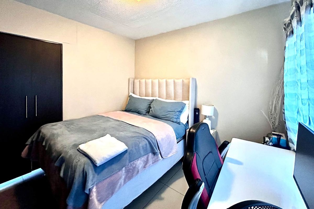 A functional bedroom featuring tiled flooring and a built-in wardrobe, providing essential storage and a neutral foundation for personalization.