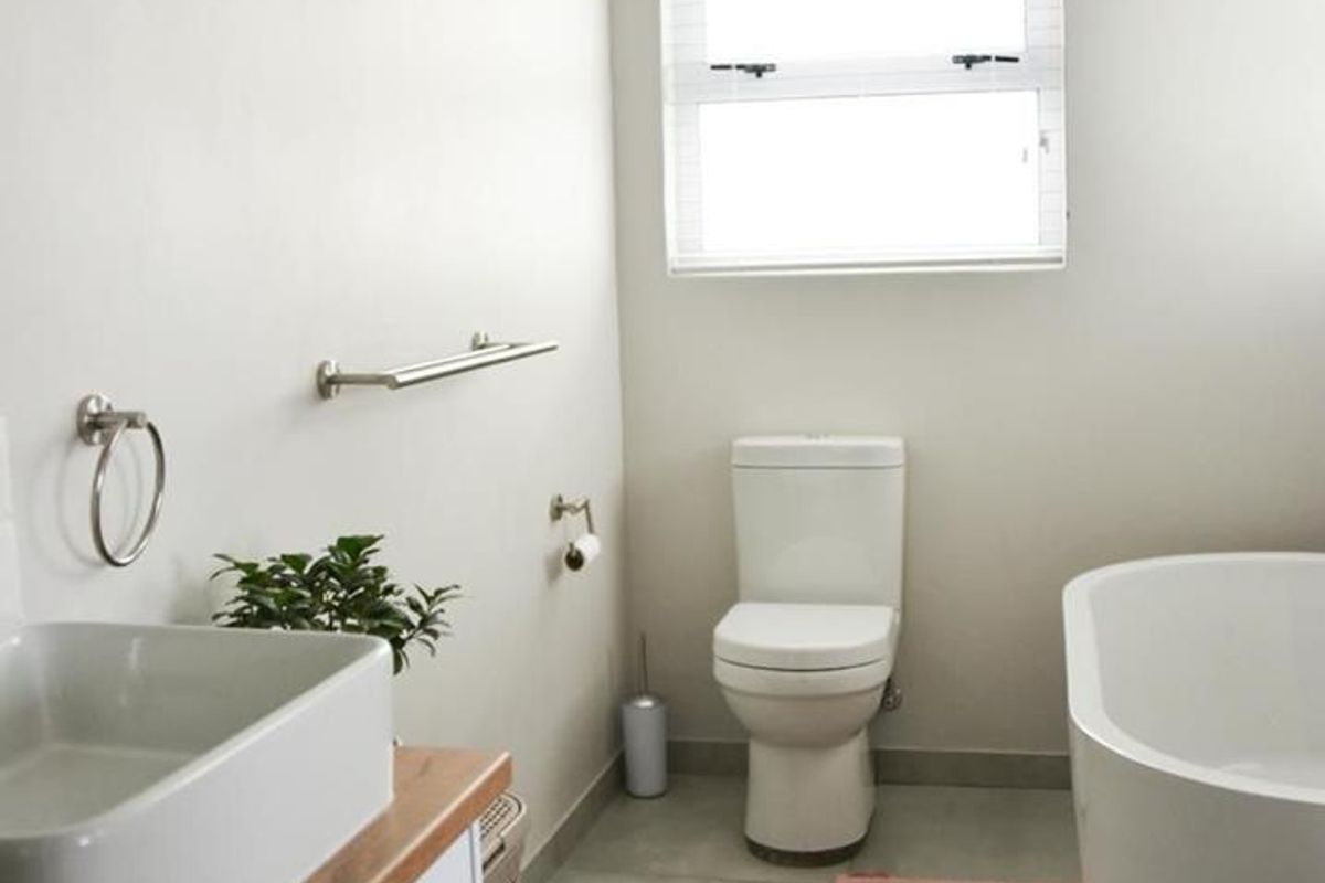 A modern bathroom featuring a freestanding bathtub, a contemporary vanity with a vessel sink, and a toilet, finished with neutral floor tiles.