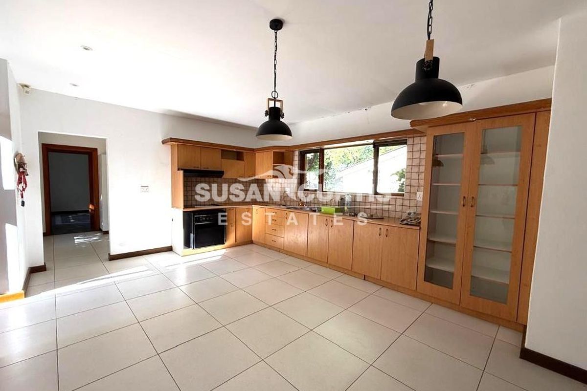 Spacious kitchen featuring light wood cabinetry, tiled flooring, built-in oven, extractor fan, and ample counter space with a tiled backsplash.