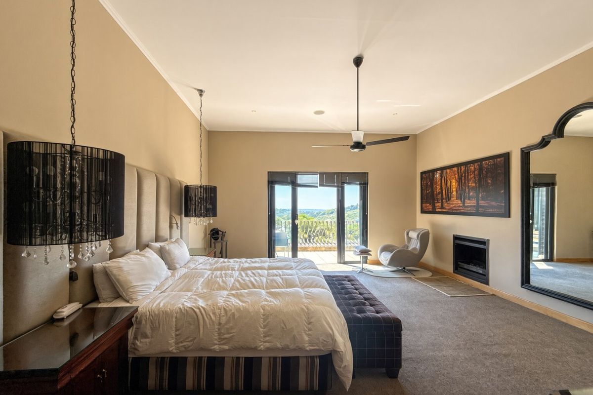 Spacious bedroom featuring a built-in fireplace, ceiling fan, and sliding glass doors leading to a private balcony with scenic views.