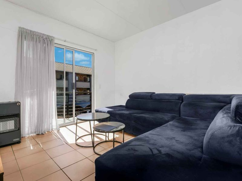 A living room featuring tiled flooring and a sliding glass door providing access to an outdoor balcony area.