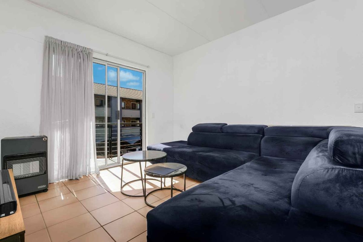 A living room featuring tiled flooring and a sliding glass door providing access to an outdoor balcony area.