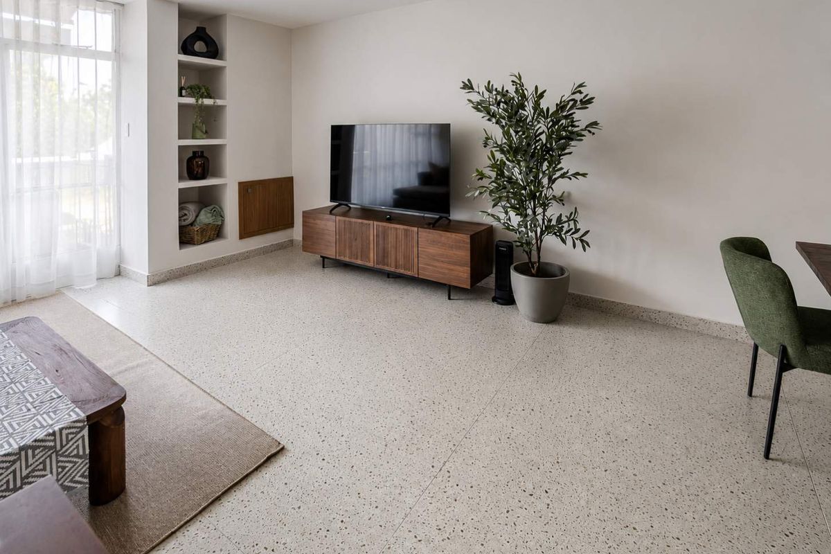 A bright and modern living room featuring high-quality terrazzo flooring and custom built-in wall shelving, offering a clean and contemporary aesthetic.
