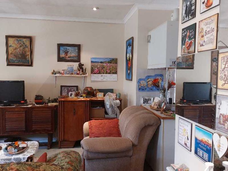 A living room area featuring coving and a mirrored wall panel, currently furnished with personal items and seating.