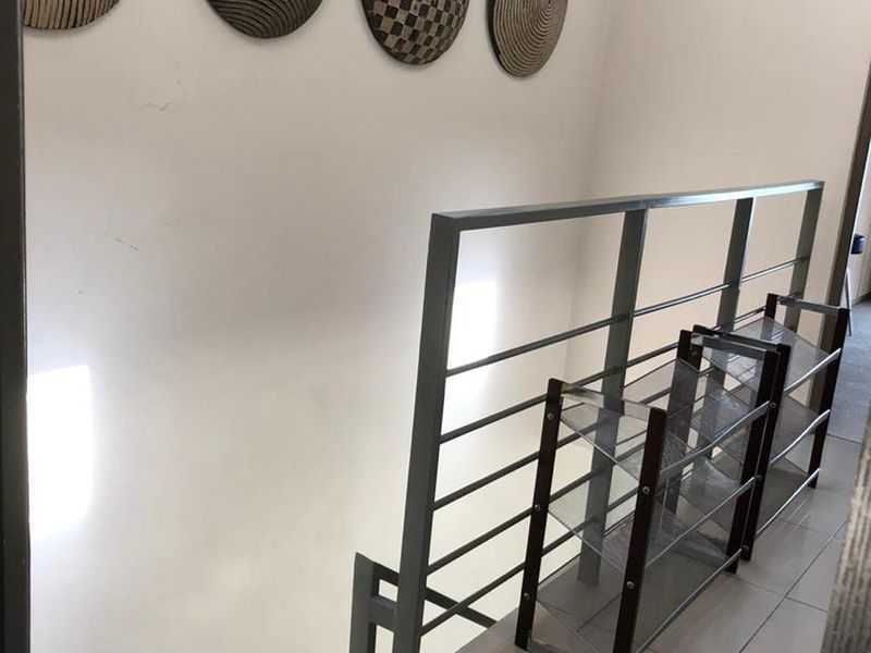 A bright hallway featuring tiled flooring and a modern metal staircase railing, providing a clean and functional transition space within the townhouse.