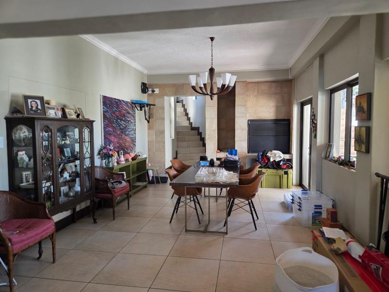 Spacious dining area featuring tiled flooring, a built-in fireplace with stone cladding, and direct access to an internal staircase.