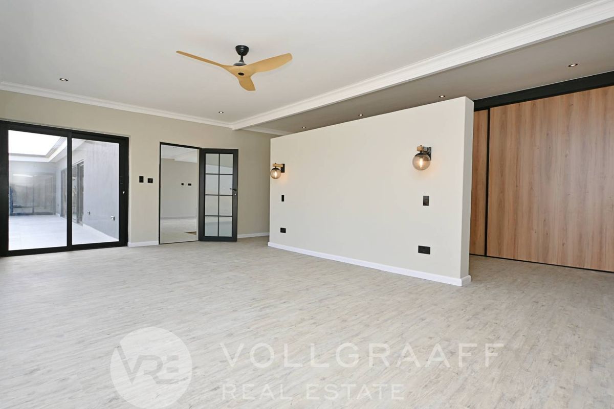 Spacious interior room featuring modern wood-look flooring, a central partition wall with integrated lighting, a ceiling fan, and sliding glass doors leading outdoors.
