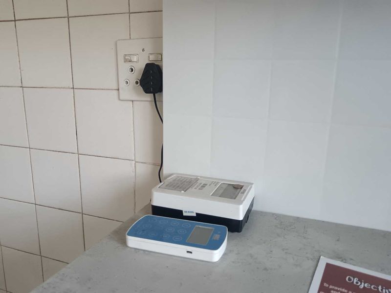 A utility area featuring a tiled splashback and a wall-mounted electrical outlet with a prepaid electricity meter unit.