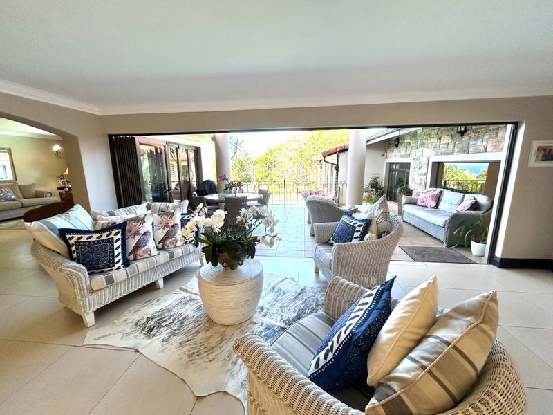 Spacious open-plan living area featuring large stacking glass doors that seamlessly connect the interior to a covered patio with stone cladding.