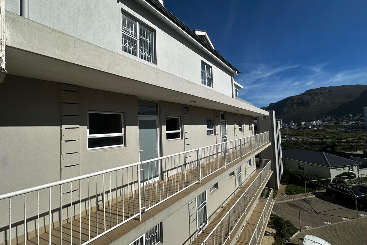 Exterior view of the apartment building featuring multiple levels of balconies with metal railings and security bars on windows.