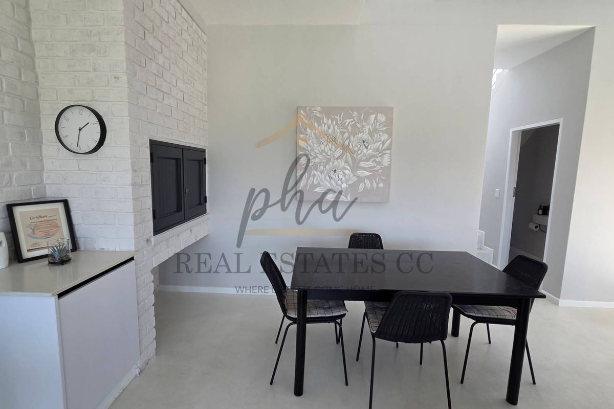 A bright living area featuring a white painted brick fireplace and smooth flooring, creating a clean and modern aesthetic.