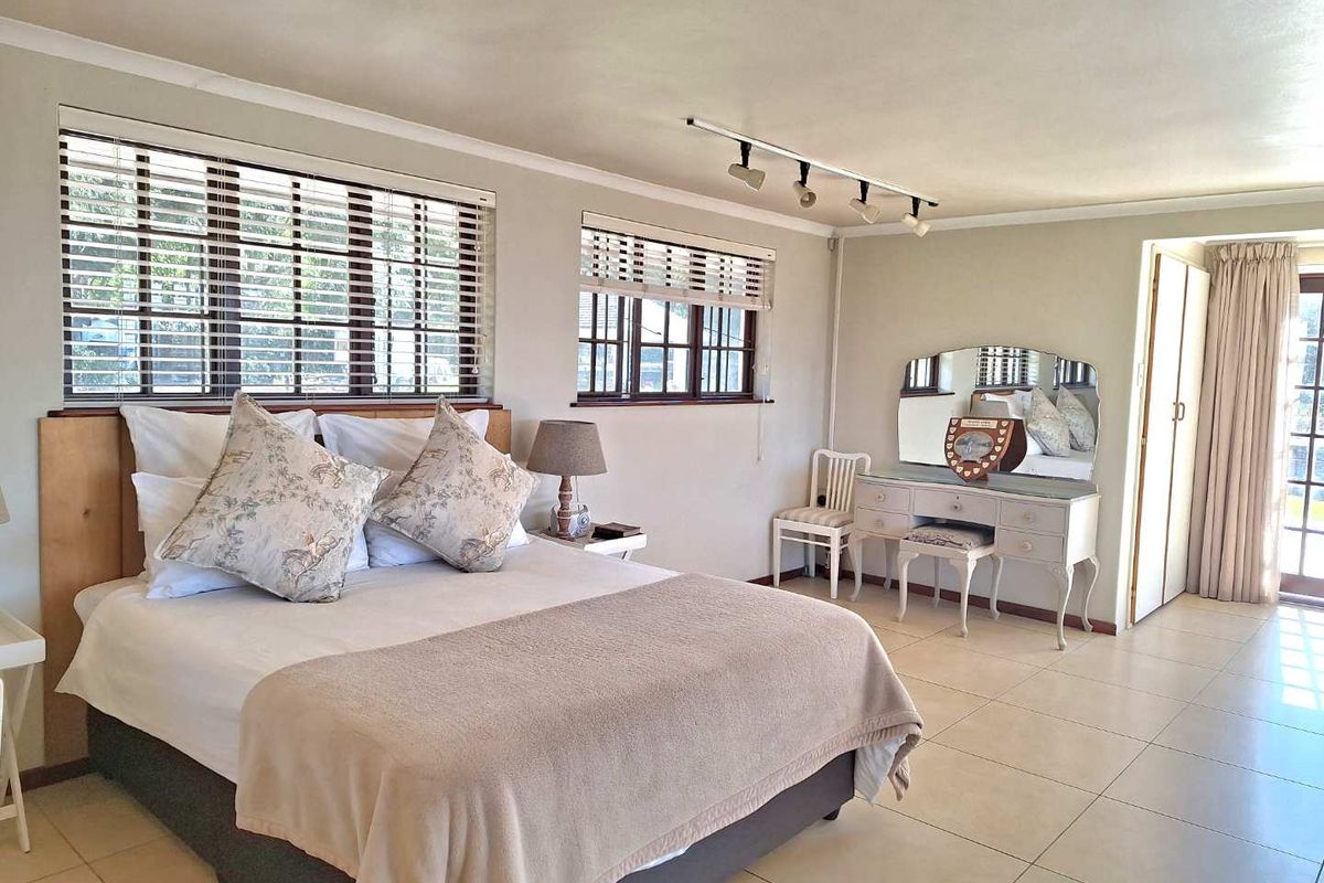 Spacious bedroom featuring neutral tiled flooring, track lighting, and built-in storage, with large windows providing ample natural light.