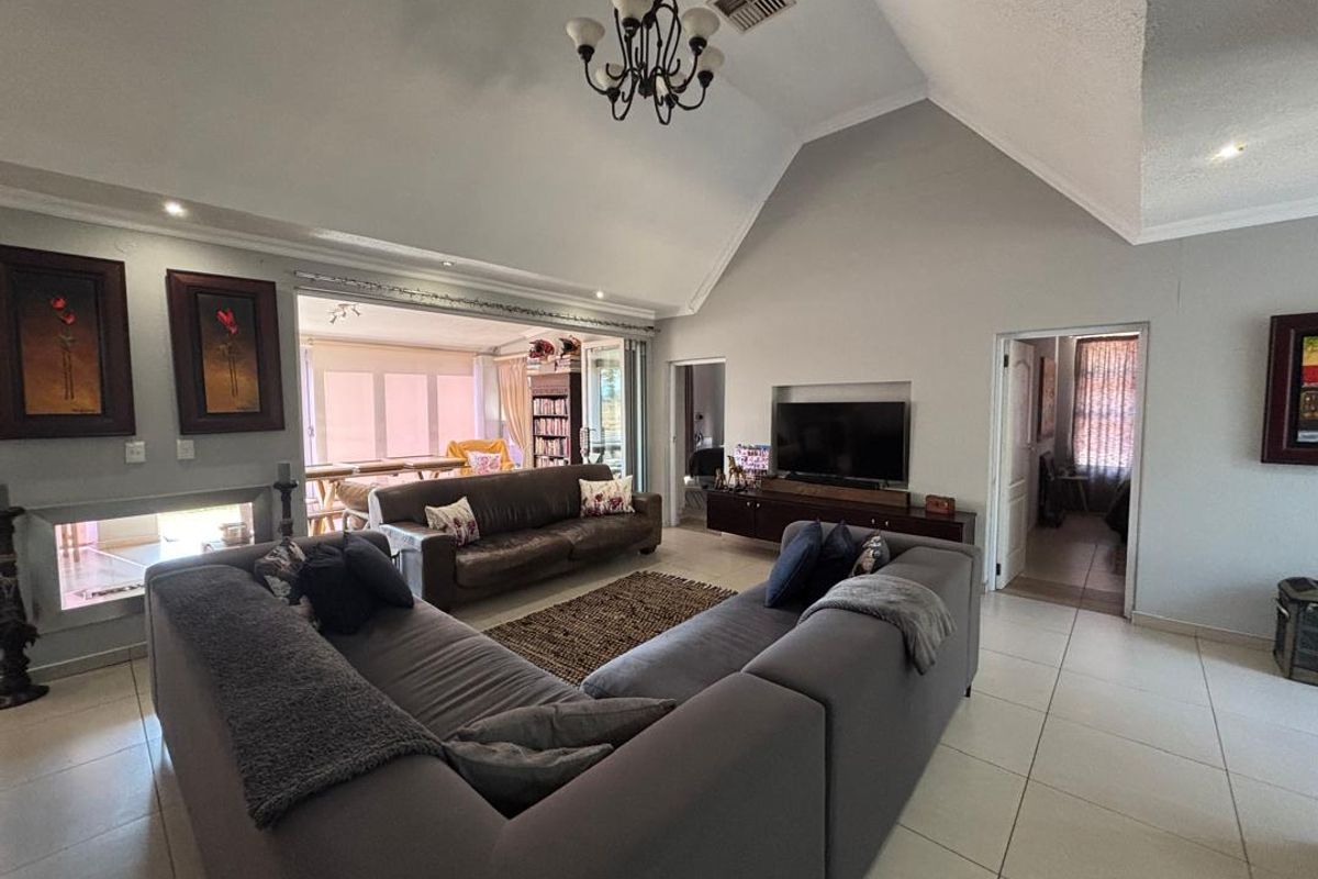 Spacious living room featuring a high vaulted ceiling, tiled flooring, a built-in fireplace, and a recessed television niche, creating an open and airy atmosphere.