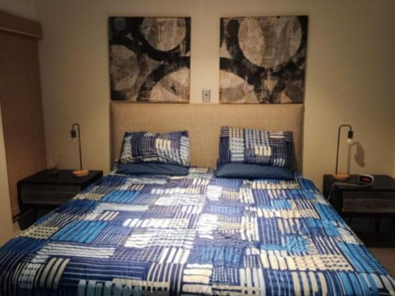 A well-maintained bedroom featuring a neutral upholstered headboard and a functional roller blind.