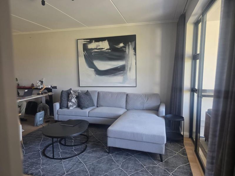 A well-lit living room featuring large glass sliding doors that provide access to an outdoor area and modern ceiling finishes.