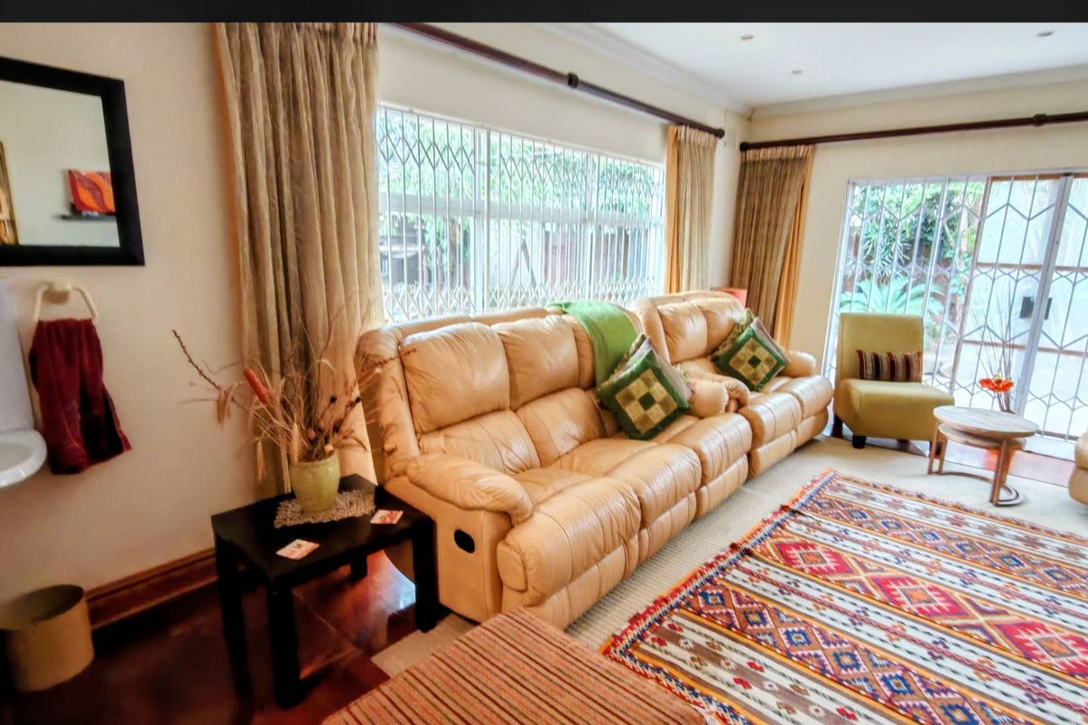 A comfortable living room featuring hardwood flooring, recessed lighting, and large windows with security gates, providing access to the outdoor area.