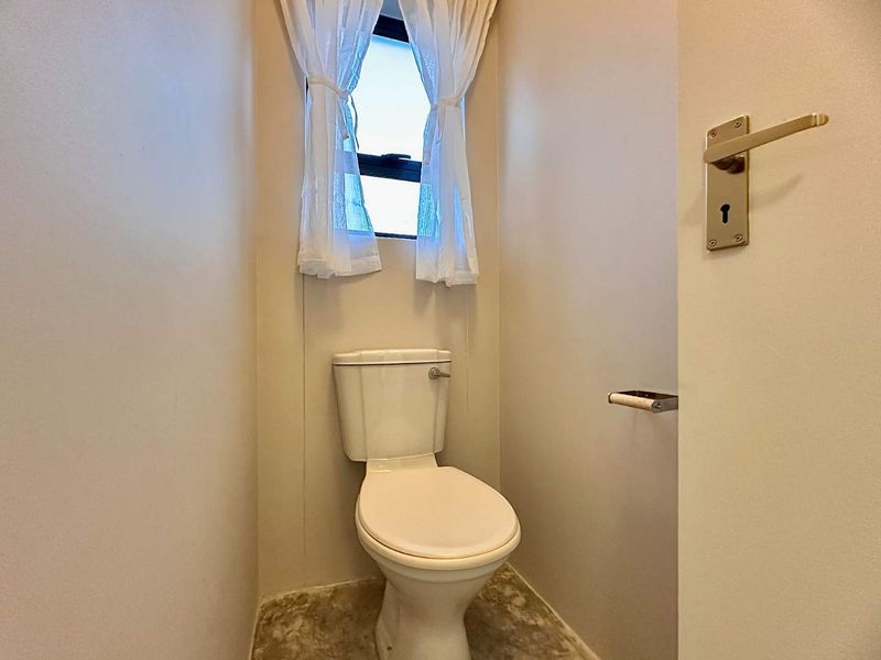 A compact guest toilet featuring a standard white toilet suite and a lever-style door handle.