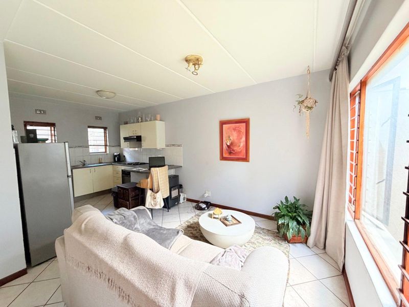 Open-plan living area featuring a functional kitchen with built-in cabinetry and tiled flooring throughout, offering a practical layout for modern apartment living.