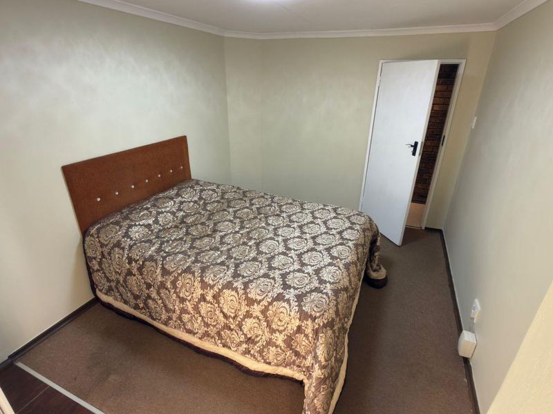 A simple bedroom featuring neutral wall paint, carpeted flooring, and a standard internal door leading to an adjacent space.