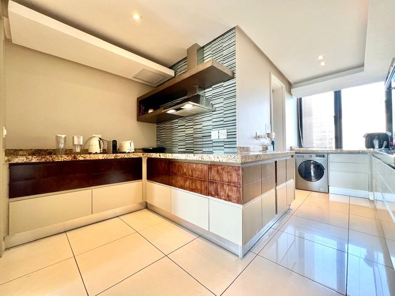 Modern kitchen featuring granite countertops, mosaic tile backsplash, built-in cabinetry, and integrated laundry space with tiled flooring and recessed lighting.