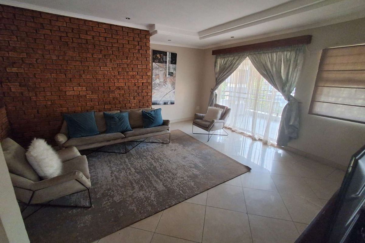 A spacious living room featuring a prominent exposed brick feature wall, tiled flooring, and large sliding doors leading to an outdoor area.