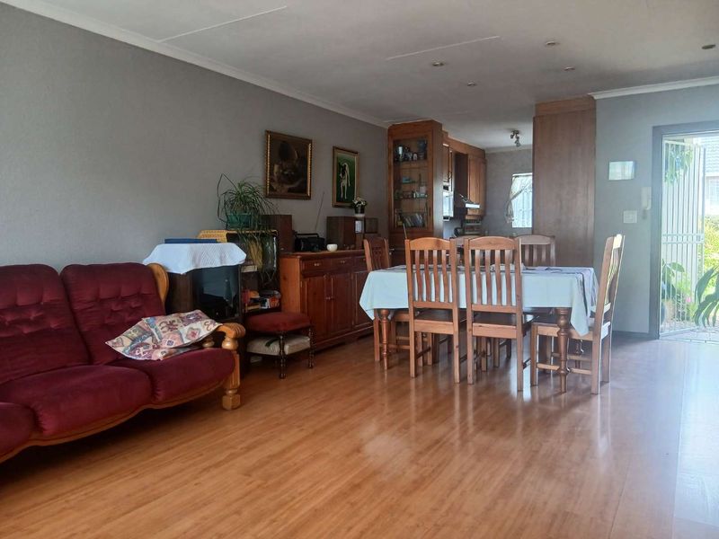 Open-plan living and dining area featuring laminate flooring, recessed lighting, and direct access to an outdoor space through a security gate.