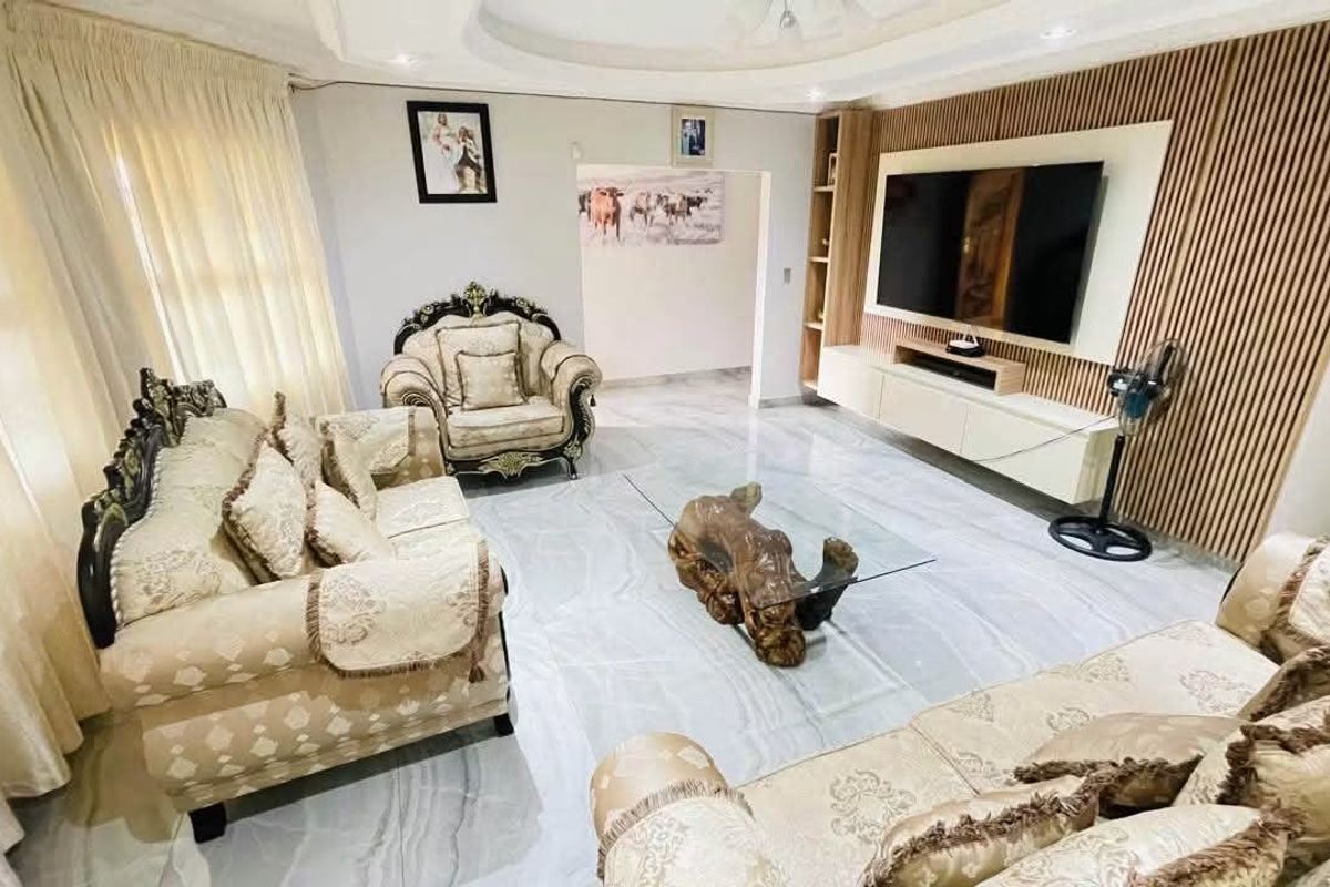 A modern living room featuring marble-look floor tiles, a decorative recessed ceiling, and a stylish slat wall paneling with a built-in media console.