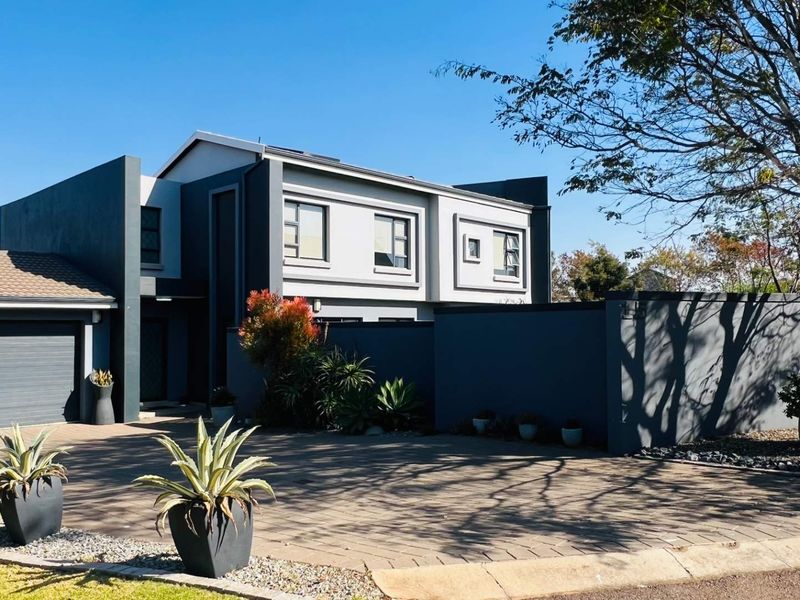 Modern double-storey residential property featuring a paved driveway, double garage, and contemporary grey facade with clean architectural lines.