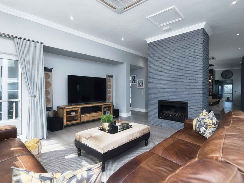 Spacious living room featuring a striking grey stone-clad fireplace, recessed ceiling lighting, and seamless access to the outdoor area through sliding glass doors.