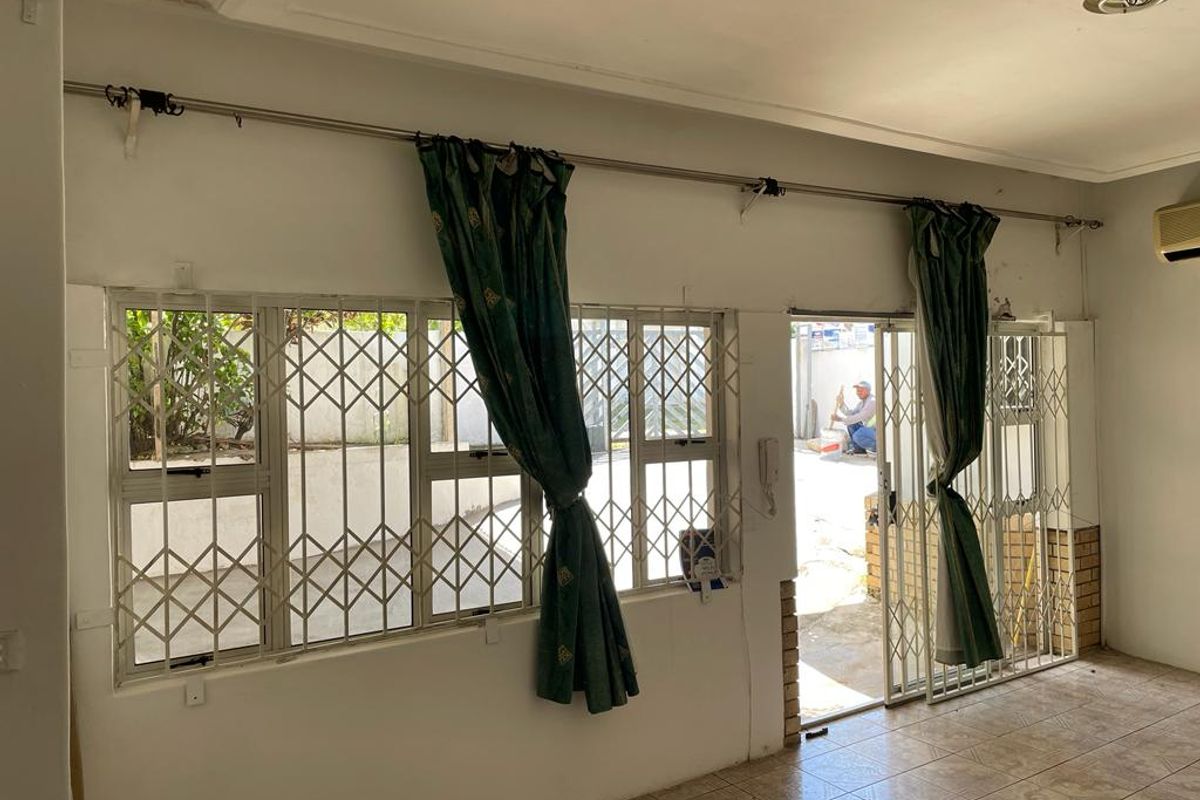 Living area featuring tiled flooring, security gates on windows and doors, and access to an outdoor space.