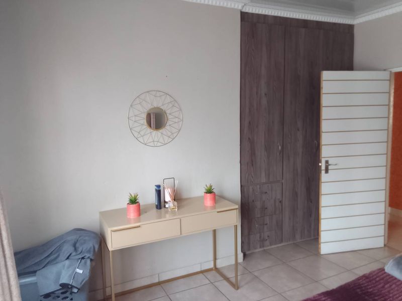 A bedroom featuring built-in wooden cupboards, tiled flooring, and decorative ceiling cornicing.