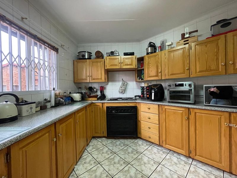 A functional kitchen featuring traditional wooden cabinetry, laminate countertops, tiled backsplash, and built-in oven with electric hob.