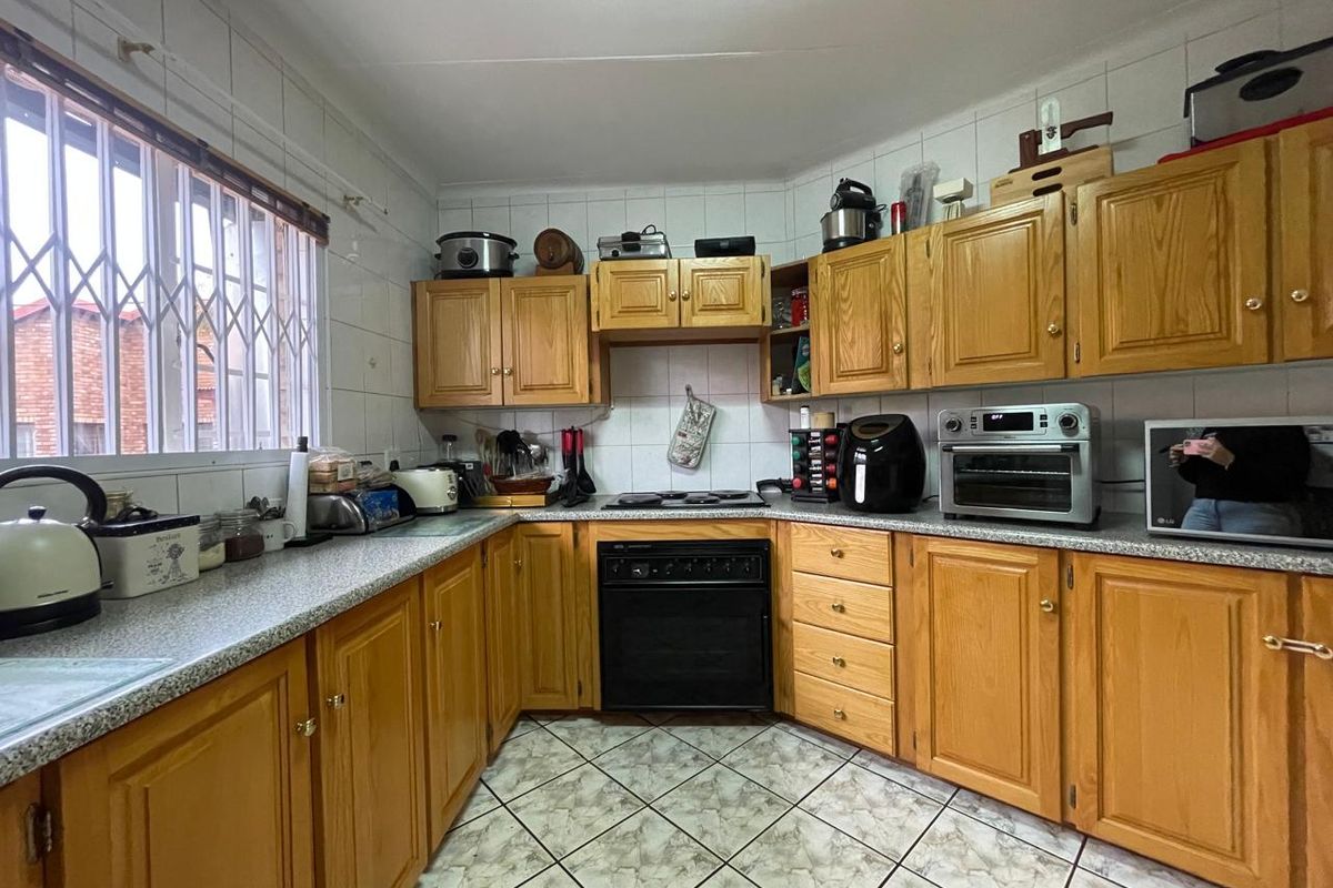 A functional kitchen featuring traditional wooden cabinetry, laminate countertops, tiled backsplash, and built-in oven with electric hob.