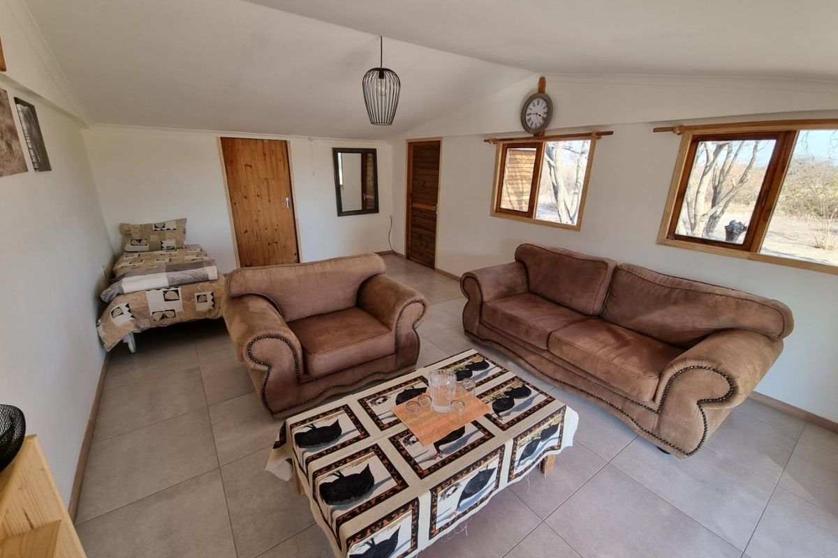 A living area featuring tiled flooring, timber door frames, and large windows providing natural light and views of the surrounding farm landscape.