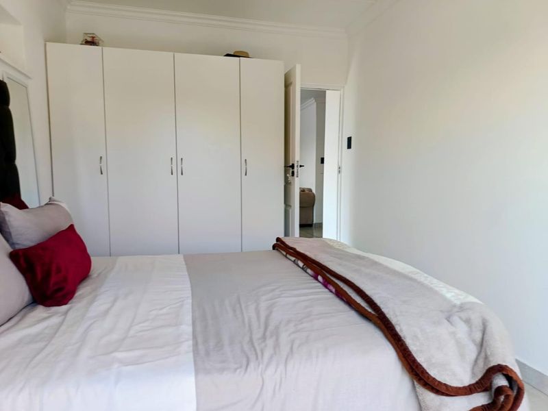 A well-maintained bedroom featuring clean white walls, neutral flooring, and ample built-in cupboard storage space.