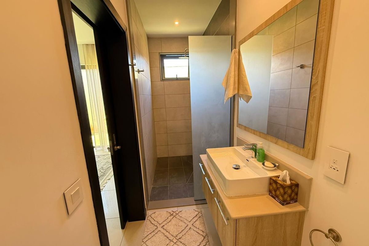 A modern bathroom featuring a floating vanity with a vessel sink, a large wall-mounted mirror, and a walk-in shower with tiled finishes.
