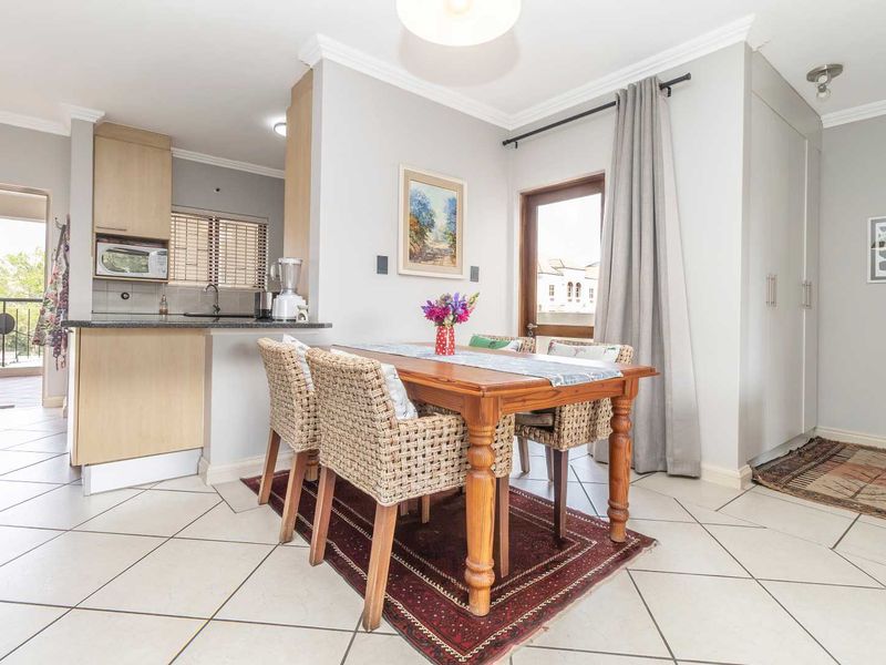 Open-plan living and dining area featuring tiled floors, built-in kitchen cabinetry with granite countertops, and direct access to a private balcony.